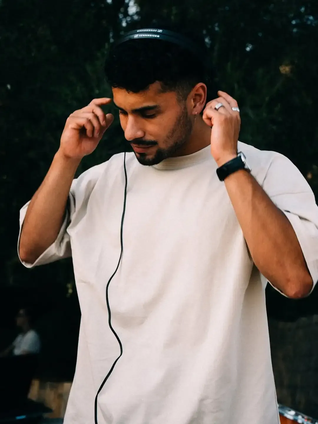 DJ Jowy pinchando en una fiesta. Está mirando hacia abajo con los cascos puestos.